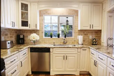 a kitchen with white cabinets and a sink and a window at Destination #26 in Anaheim