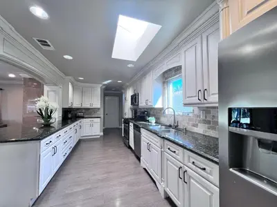 a large kitchen with white cabinets and black counter tops at Destination #33 in Orange