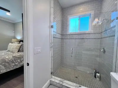 a bathroom with a walk in shower next to a bed at Destination #34 in Santa Ana