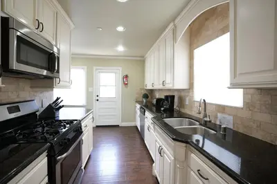 a kitchen with white cabinets and a sink and a stove at Classy PoolJac Home: 2 Ensuites 34 Mile2Disney in Anaheim