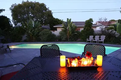 a table with candles and chairs next to a swimming pool at Destination #15 in Anaheim