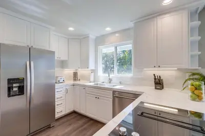 a kitchen with white cabinets and a stainless steel refrigerator at Destination #44 in Orange