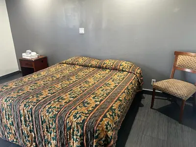 a hotel room with a bed and a chair at Pomona Inn in Pomona