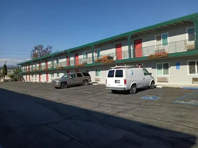 two cars parked in a parking lot in front of a building at Pomona Inn in Pomona