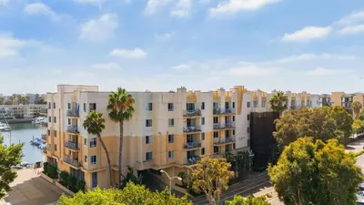 an apartment building with palm trees next to a river at The Blossom-Modern 1BR Getaway in Marina Walk to Water&Restaurants in Los Angeles