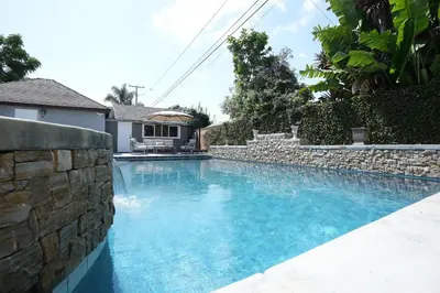 a swimming pool with a stone wall next to a house at Destination #51 in Santa Ana