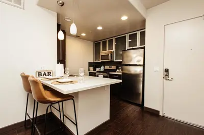 a kitchen with a bar with chairs and a refrigerator at Beautiful Studio in West Hollywood in Los Angeles
