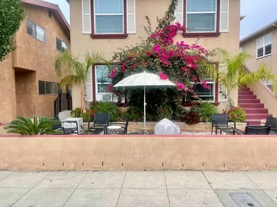 a patio with chairs and an umbrella in front of a building at Belmont Shore Beach Bungalow, 2 min walk to town! in Long Beach