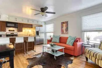 a living room with a red couch and a kitchen at Belmont Shore Beach Bungalow, 2 min walk to town! in Long Beach