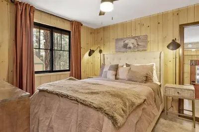 a bedroom with a large bed and wooden walls at Bruin Chalet Big Bear~ Cozy Single Level Retreat Cottage~ in Big Bear Lake