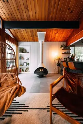 a living room with a fireplace in the middle of a room at Lightfoot Cabin Mid-Century Perfect Romantic Getaway Hot Tub Sauna in Running Springs