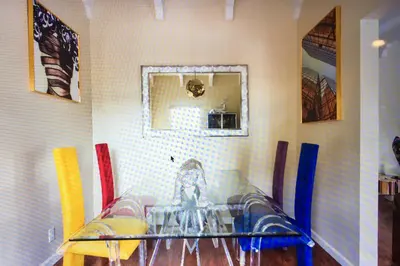 a dining room with a glass table and colorful chairs at Luxury 2 Bedroom Suite Apartment in Koreatown in Los Angeles