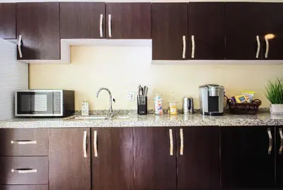a kitchen with wooden cabinets and a counter top with a microwave at Luxury 2 Bedroom Suite Apartment in Koreatown in Los Angeles