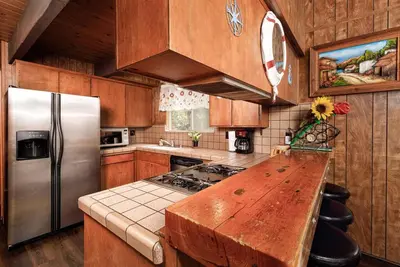 a kitchen with wooden cabinets and a stainless steel refrigerator at Classic AFrame - Fireplace - GameRoom - 2 Decks View in Lake Arrowhead