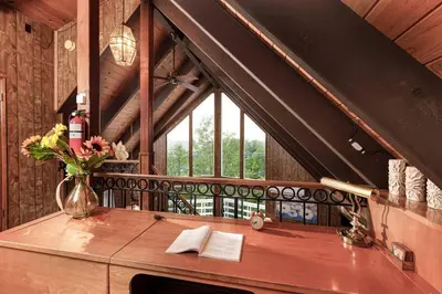 a vase of flowers on a wooden table with a window at Classic AFrame - Fireplace - GameRoom - 2 Decks View in Lake Arrowhead