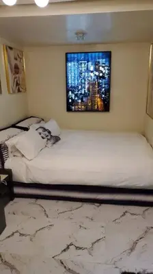 a bedroom with a white bed with a painting on the wall at Stylish Apartment in Koreatown! Central Location!! in Los Angeles