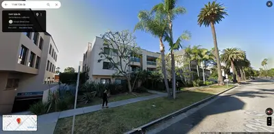 a person riding a skateboard down a street with palm trees at Chic Retreat by Santa Monica in Los Angeles
