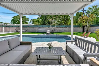 a patio with a couch and a table and a pool at New cheerful villa, Pool, Spa, Mini Golf, Game room, Fire pit next to Disneyland in Anaheim