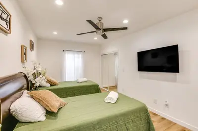 two green beds in a room with a flat screen tv at 7 Mi to Dtwn! Modern Retreat in East Los Angeles in East Los Angeles