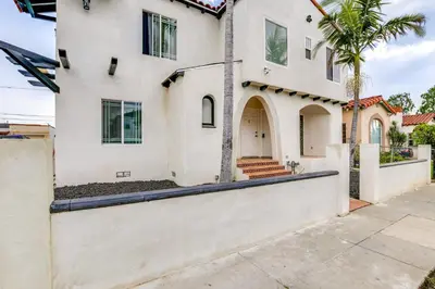 a white house with a gate and a palm tree at 7 Mi to Dtwn! Modern Retreat in East Los Angeles in East Los Angeles