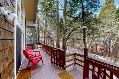 a wooden porch with a red chair on it at Fernrock Cabin in Twin Peaks