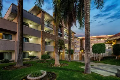 a large building with palm trees in front of it at La Quinta by Wyndham Pomona in Pomona