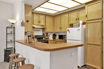 a kitchen with wooden cabinets and a white refrigerator at Restmoore Big Bear~ Lakeside Condo Retreat~ in Big Bear Lake