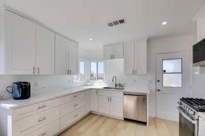 a white kitchen with white cabinets and a sink at 5 Mi to Venice Beach Chic Los Angeles Abode in Los Angeles