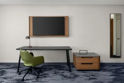 a desk with a chair and a television on a wall at Fairfield by Marriott Inn & Suites Victorville in Victorville