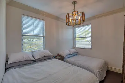 two beds in a bedroom with a chandelier and two windows at Luxury 2 bed 1 bath in Torrance