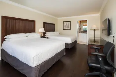 a hotel room with two beds and a desk with a chair at Bokai Garden Hotel in Rosemead