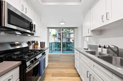 a kitchen with white cabinets and a stove top oven at The Turquoise Lounge - Chic 2BR Beach view Pool, Sauna in Los Angeles