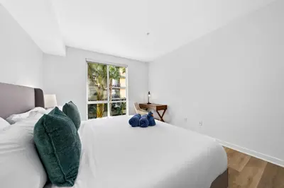 a white bedroom with a white bed with green pillows at The Turquoise Lounge - Chic 2BR Beach view Pool, Sauna in Los Angeles
