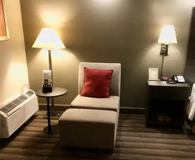 a room with a chair with a red pillow on it at GreenTree Inn & Suites Los Angeles - Alhambra - Pasadena in Alhambra