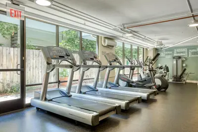 a row of cardio machines in a gym with windows at Pasadena 1BR w gym pool nr Colorado Ave LAX-861 in Pasadena