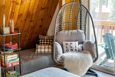 a swinging chair in a room with a window at Cozy Cabin near Resorts and The Village +Mtn views in Big Bear City