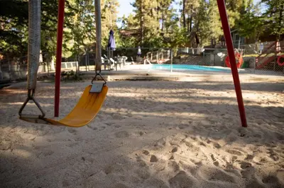 a swing seat in a park with a playground at Sunset Cottage Lakeside Couple's Cabin by Big Bear Vacations in Big Bear Lake