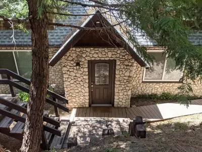 a house with a wooden door and a tree at “The Grey Haven” – Secluded home in the woods in Lake Arrowhead