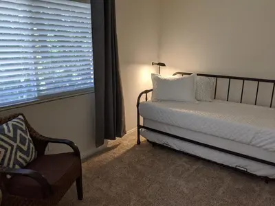 a bedroom with a bed and a chair and a window at “The Grey Haven” – Secluded home in the woods in Lake Arrowhead
