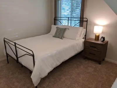 a bedroom with a bed and a night stand with a lamp at “The Grey Haven” – Secluded home in the woods in Lake Arrowhead