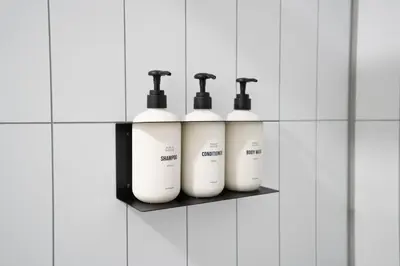 four white shampoo bottles on a shelf in a bathroom at Aliza Hotel in Los Angeles
