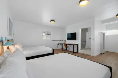 a white room with two beds and a table at Aliza Hotel in Los Angeles