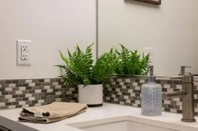 a bathroom sink with two potted plants and a mirror at Cozy 3bed Condo with balcony and a rooftop pool in Los Angeles