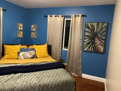 a bedroom with blue walls and a bed with yellow pillows at Big & Cozy Duplex Home in Los Angeles