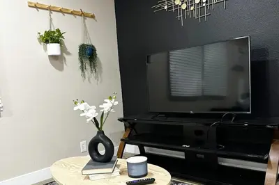 a living room with a television and a table with flowers at Modern Home Near Ontario Airport in Ontario