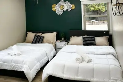 two beds in a room with a green wall at Modern Home Near Ontario Airport in Ontario
