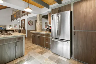 a kitchen with a stainless steel refrigerator and wooden cabinets at Evergreen -LUXURY CABIN WITH A HOT TUB, GAME ROOM & 3 EN-SUITE BEDROOMS! in Big Bear Lake