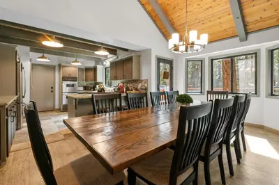 a kitchen and dining room with a wooden table and chairs at Evergreen -LUXURY CABIN WITH A HOT TUB, GAME ROOM & 3 EN-SUITE BEDROOMS! in Big Bear Lake
