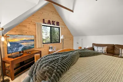 a bedroom with a large bed and a large window at Evergreen -LUXURY CABIN WITH A HOT TUB, GAME ROOM & 3 EN-SUITE BEDROOMS! in Big Bear Lake