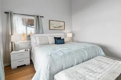 a white bedroom with a bed and a window at Lakehouse Retreat - Community Pool, Lake Views and Walk to Village! in Big Bear Lake